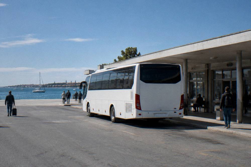 A white shuttle bus parked outside a small terminal building on a clear day.