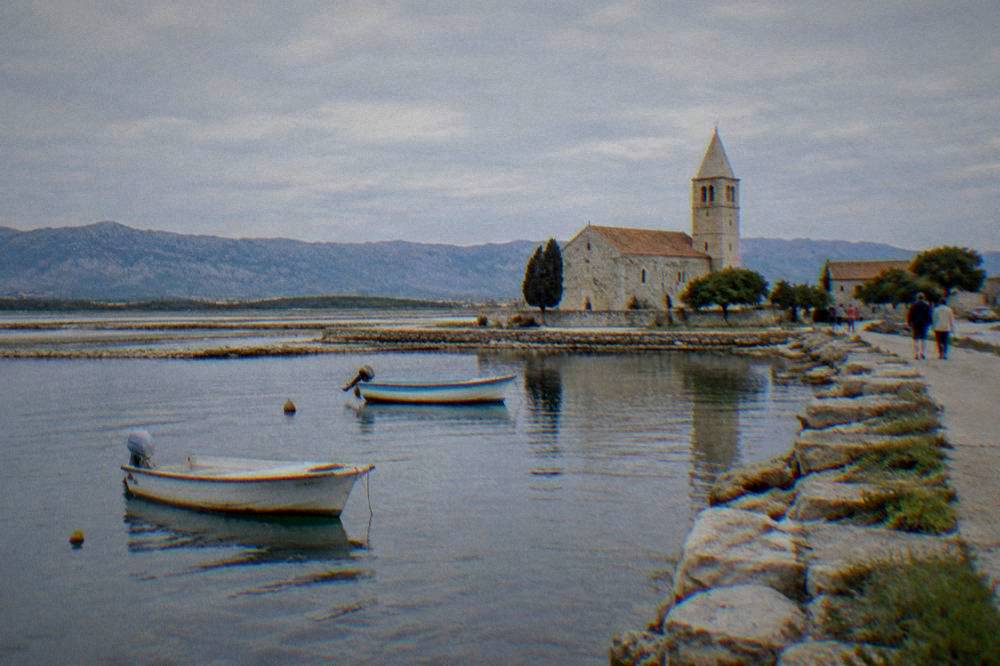 A small historic town on a lagoon with a stone church and shallow water.
