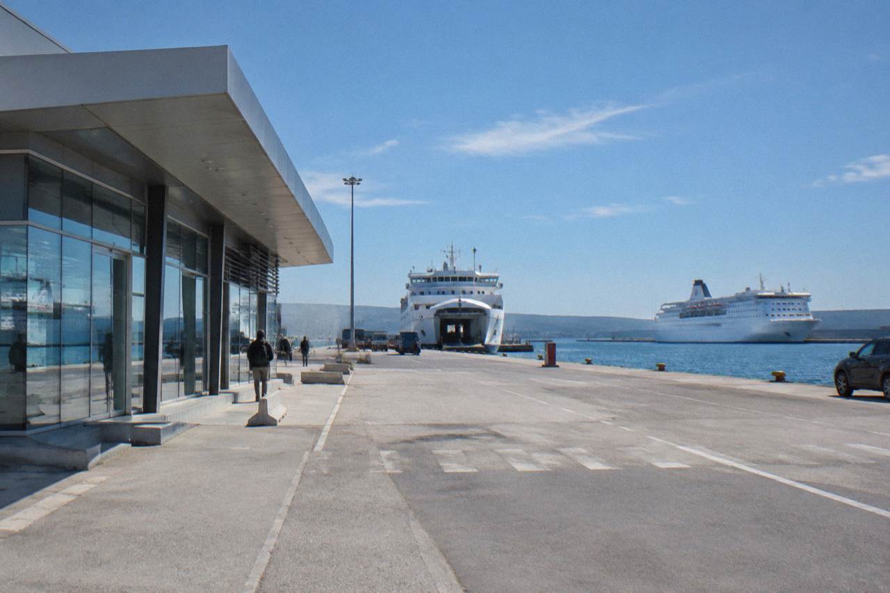 A ferry terminal building at a Croatian port with moored ships behind.