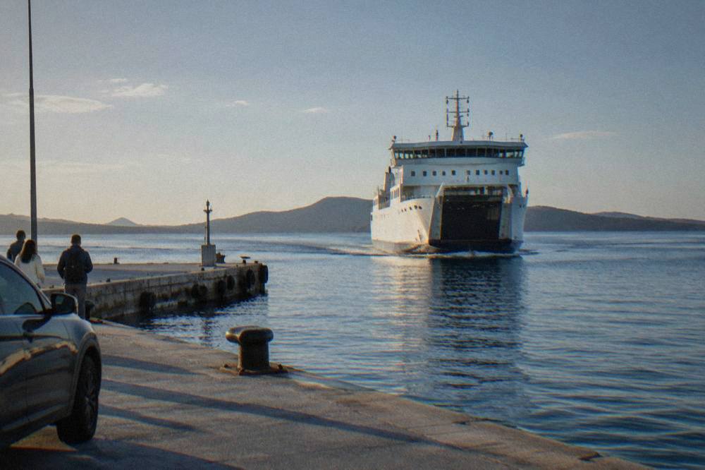 A large car ferry approaching a jetty at a Dalmatian port in morning light.