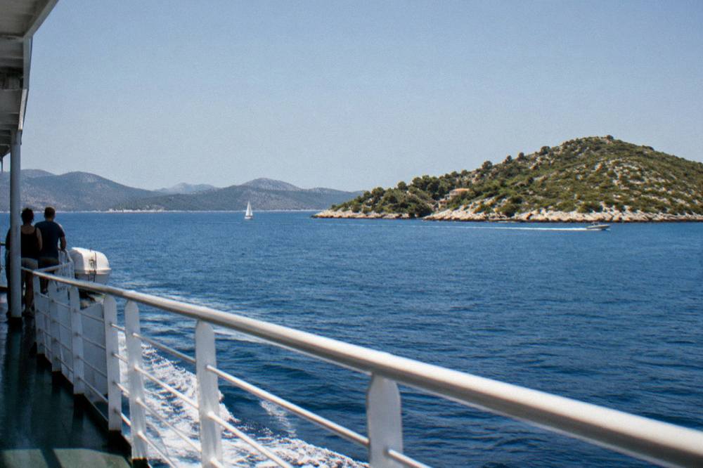 A ferry deck view of islands and open Adriatic sea under a clear sky.