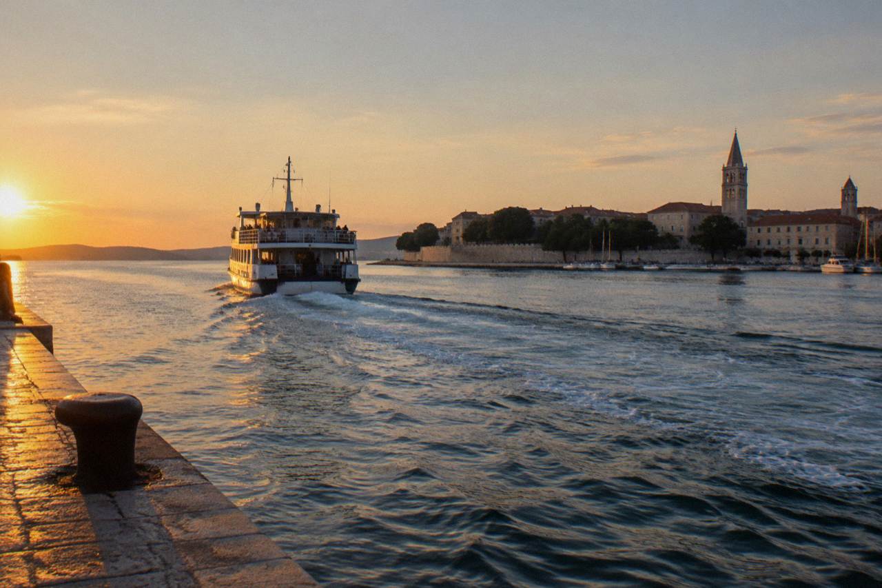 A ferry departing from Zadar harbour in late afternoon with the Old Town behind.