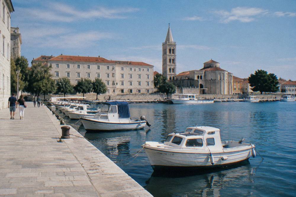 The passenger waterfront of Zadar Old Town with moored boats and pale walls.