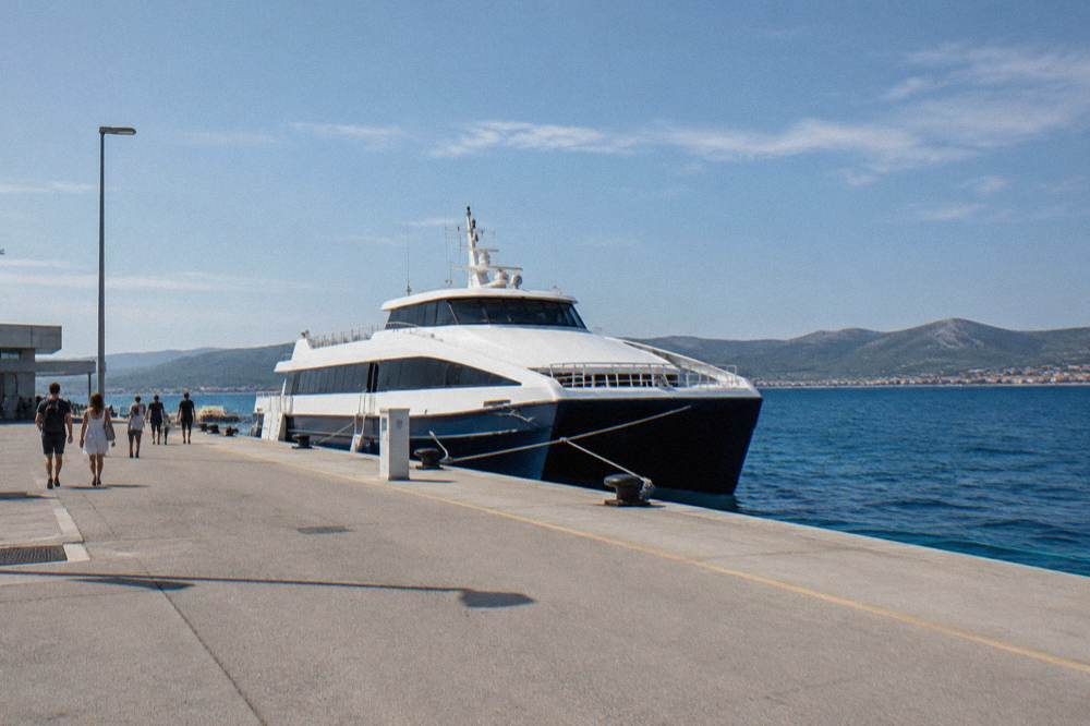 A fast catamaran moored at a seafront terminal beside a wide quay.