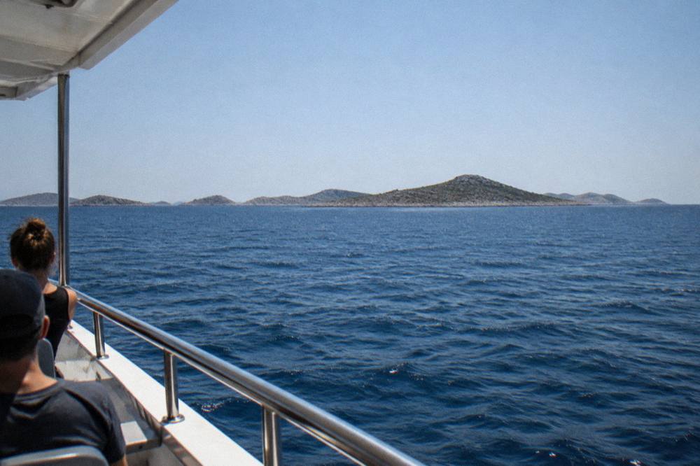 A line of small islands on the horizon seen from a boat deck.