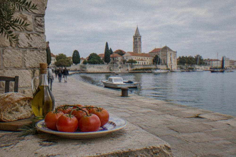Tomatoes, bread and olive oil on a sunlit stone ledge in Zadar old town.