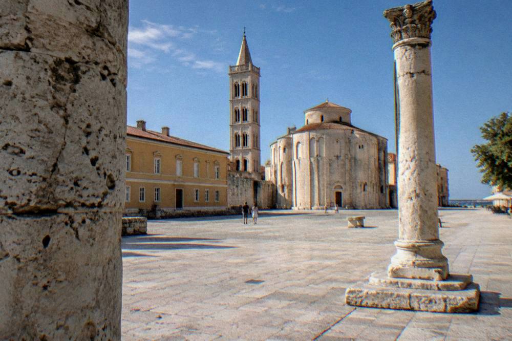 A weathered stone column in a quiet limestone square in Zadar old town.