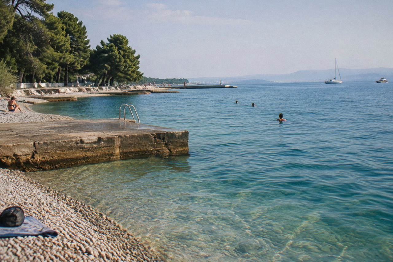 Clear turquoise water and bathing platforms at Kolovare Beach in Zadar on a summer morning.