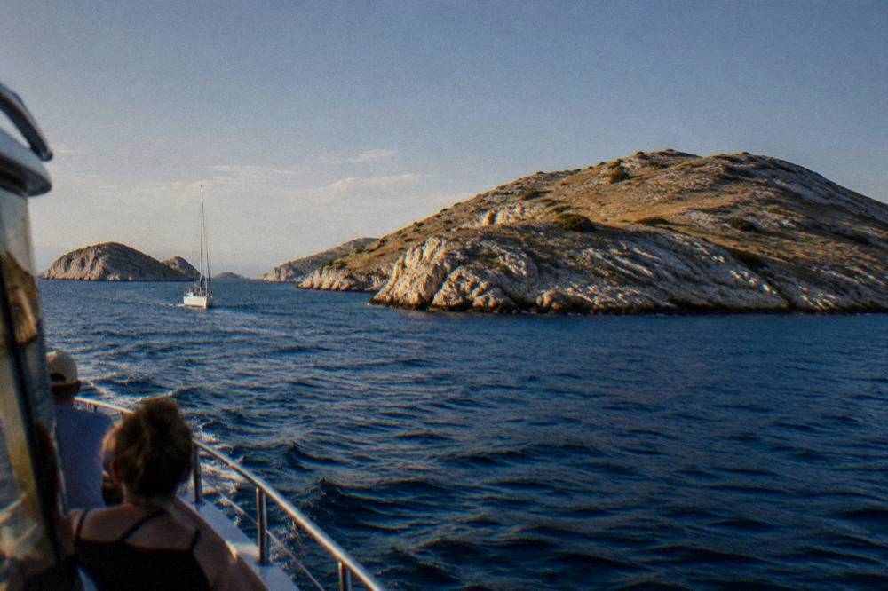 Bare rocky Kornati islets rising from deep blue sea seen from a boat.