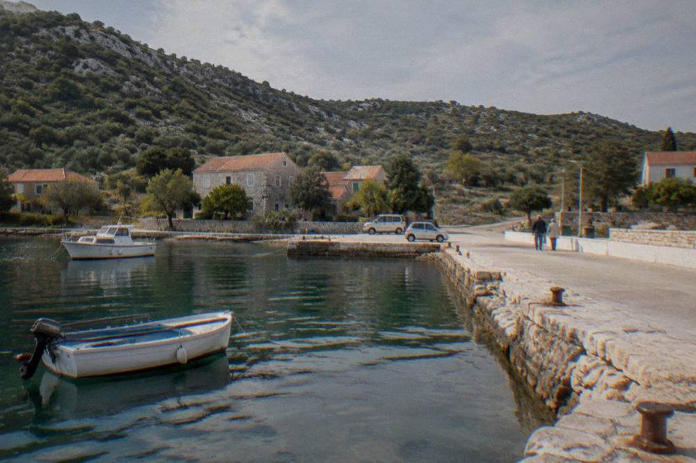 The small ferry quay at Brbinj on Dugi Otok with calm green water and dry hills.