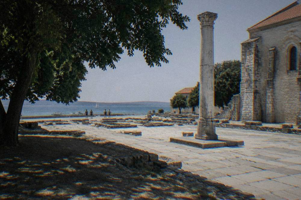 Stone paving and a Roman column beside an old stone museum building in Zadar.