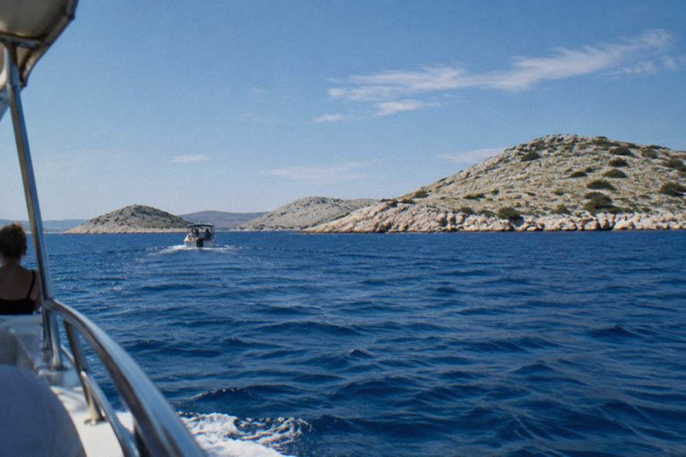 Rocky, almost treeless Kornati islands seen from a boat on deep blue water.