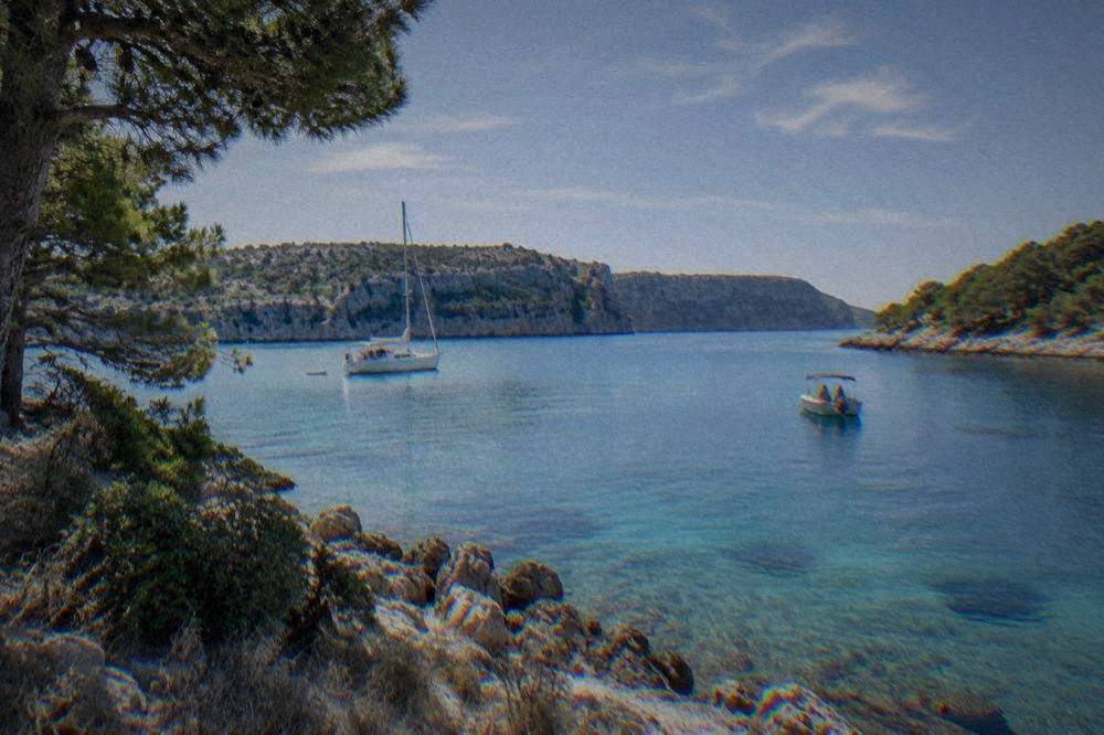 A calm turquoise bay with pines and a rocky shore in Telašćica Nature Park.