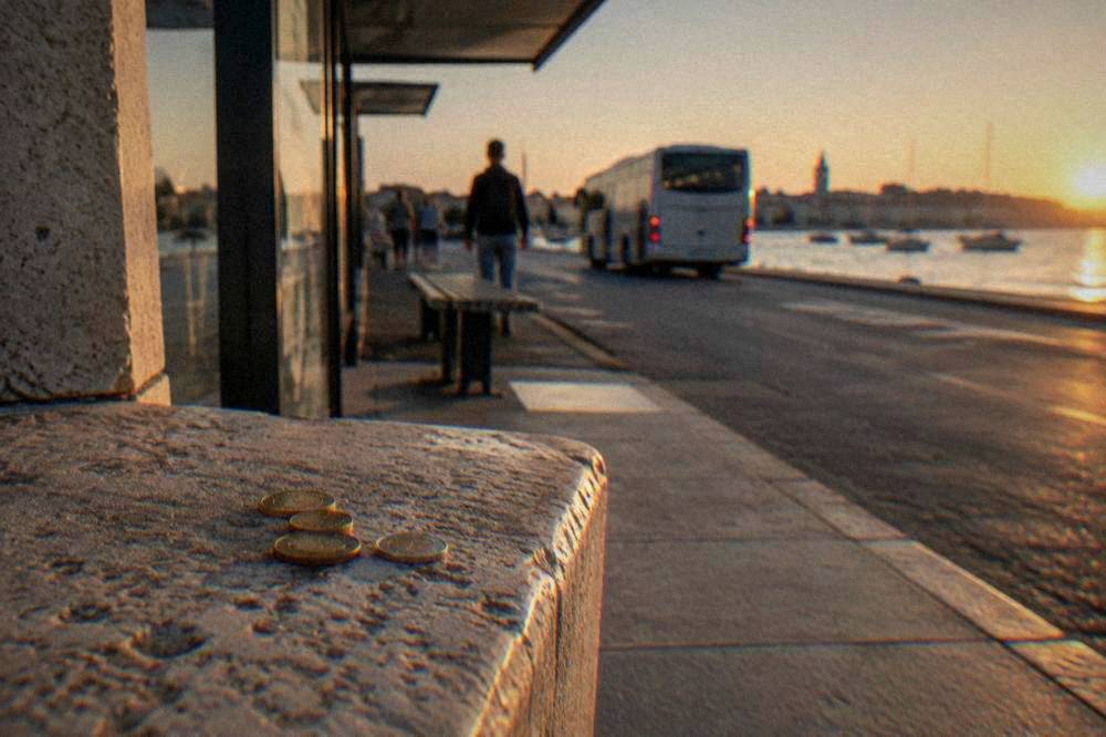 Coins on a stone ledge near a bus stop shelter in Zadar.