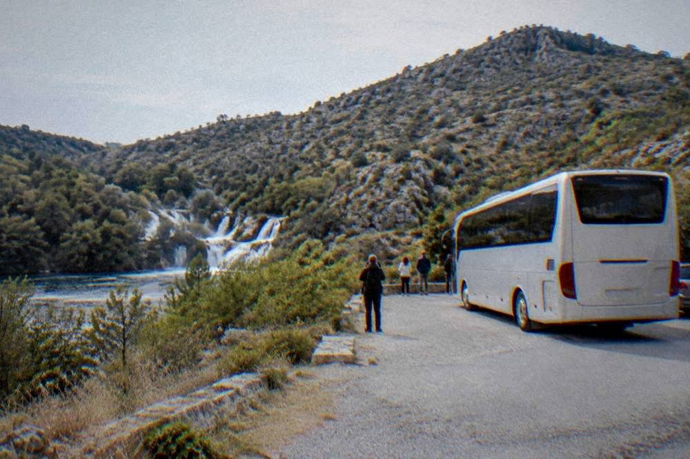 A coach parked in a lay-by with karst hills behind in inland Dalmatia.