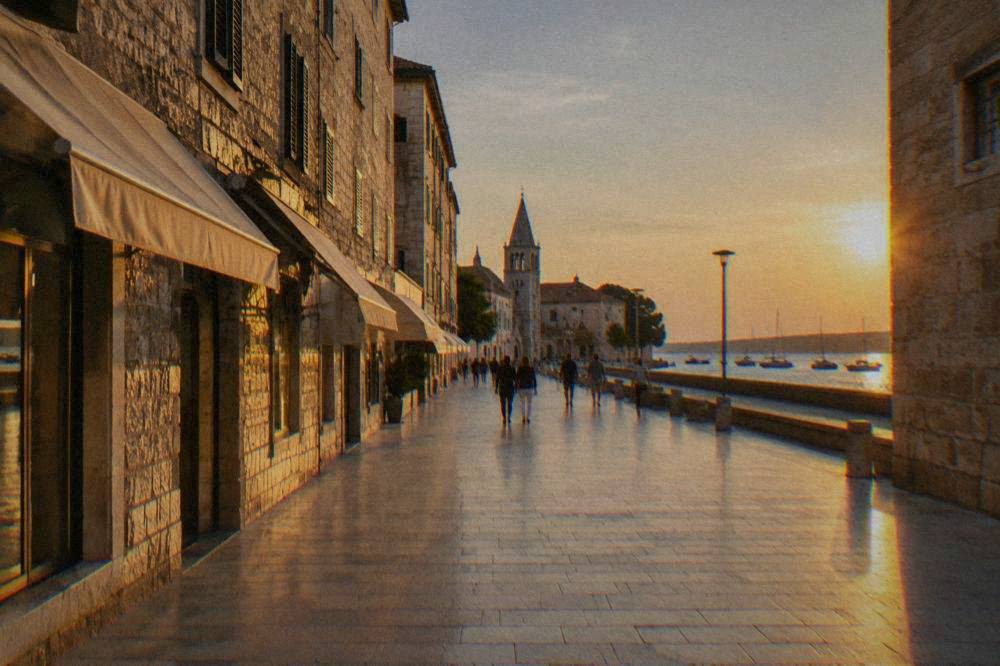 Distant strollers on the wide limestone Kalelarga street in Zadar on a calm morning.