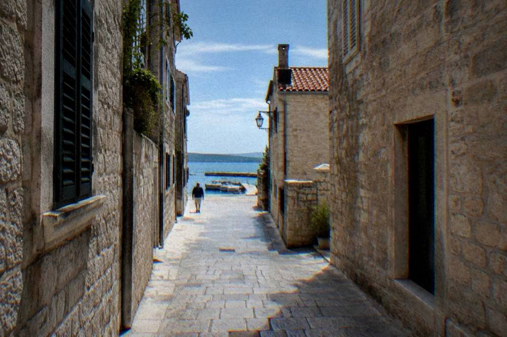 A narrow limestone lane in Zadar old town with worn paving and stone houses.