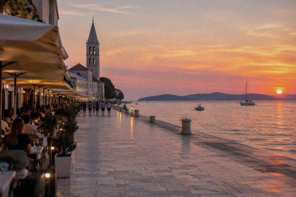 Cafe terraces along the wide limestone Kalelarga in Zadar in early evening.