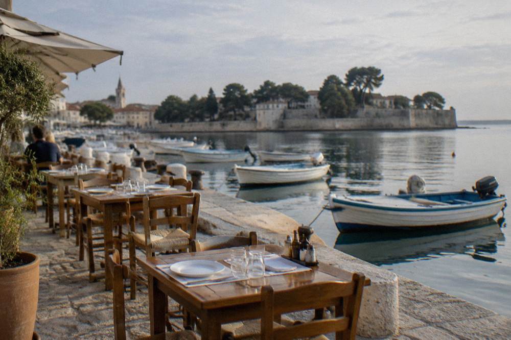 A harbourside restaurant terrace with fishing rowboats below at Foša in Zadar.