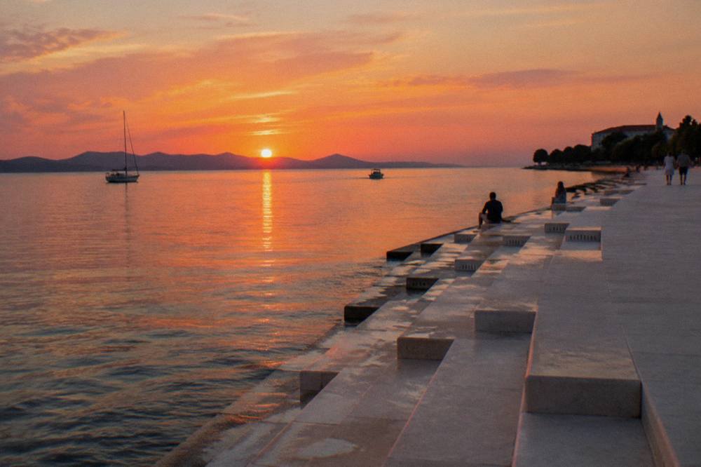 Seafront near the Sea Organ in late afternoon light in Zadar with calm sea.