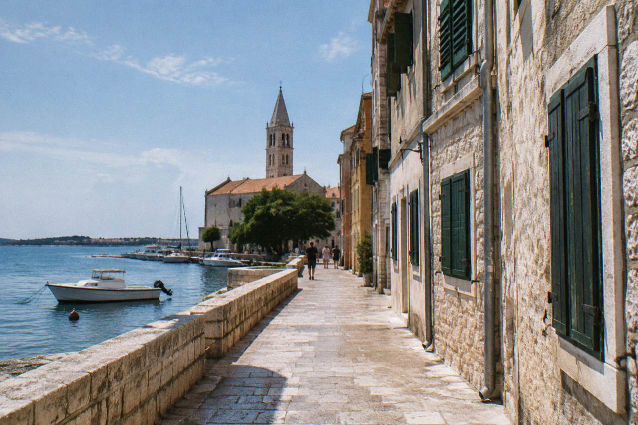 A calm limestone lane in Zadar old town with a few distant strollers.