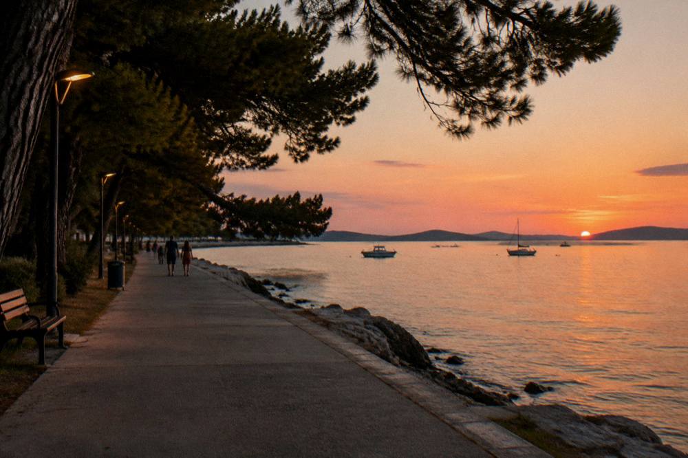 A pine-lined evening promenade at Borik in Zadar with lamps and calm sea.