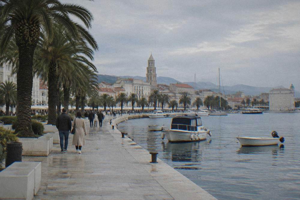 Split Riva waterfront with palms and a stone promenade beside a calm harbour.