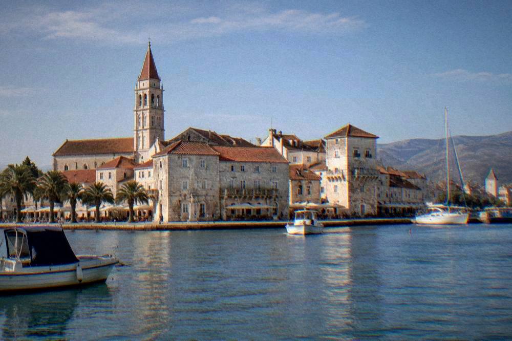 Trogir's old town on its small island with a bell tower beside calm water.