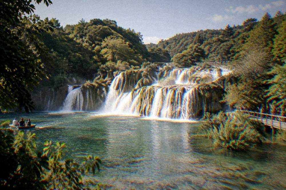 Skradinski Buk waterfalls spilling over travertine terraces with tiny visitors on the boardwalk.