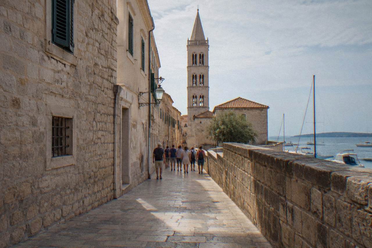 A distant tour group walking through the limestone lanes of Zadar old town.