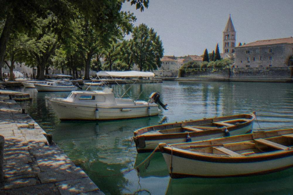 An excursion boat tied at the quay at Foša harbour beside wooden rowboats in Zadar.