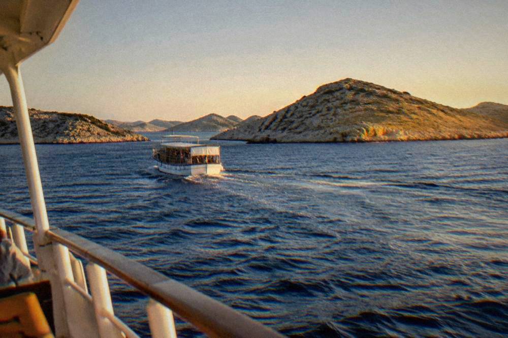 A boat cruising among bare Kornati islets on deep blue sea.