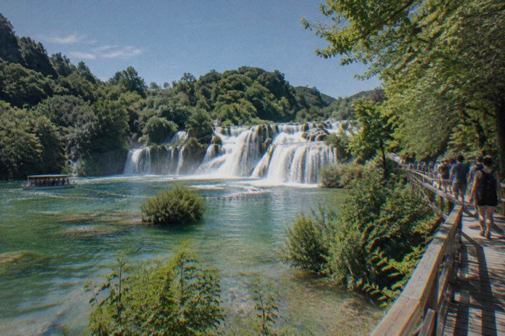 Skradinski Buk falls with a boardwalk along green pools and trees.