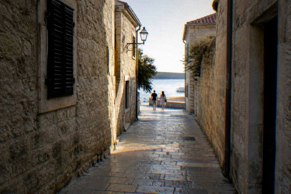 A narrow limestone lane in Zadar old town with a distant couple walking.