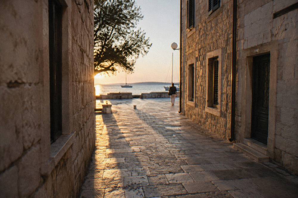 Pedestrian limestone lanes of Zadar old town with no cars and a distant walker.