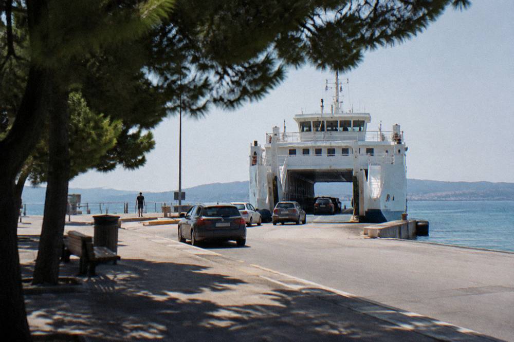 Cars waiting on the quay at Gaženica port with a ferry docked in the morning.