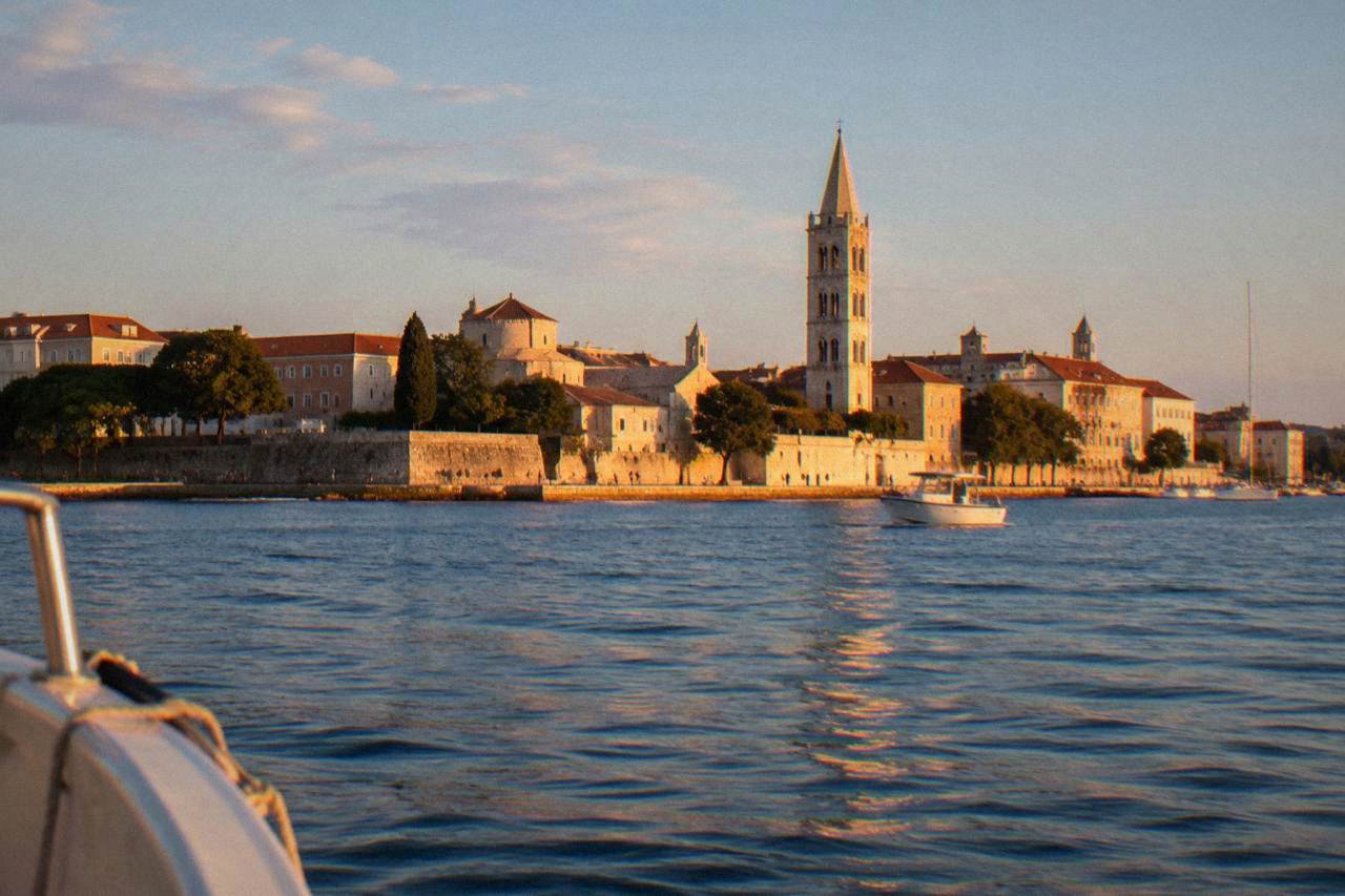 Zadar peninsula from the water with terracotta roofs, bell tower and limestone waterfront.