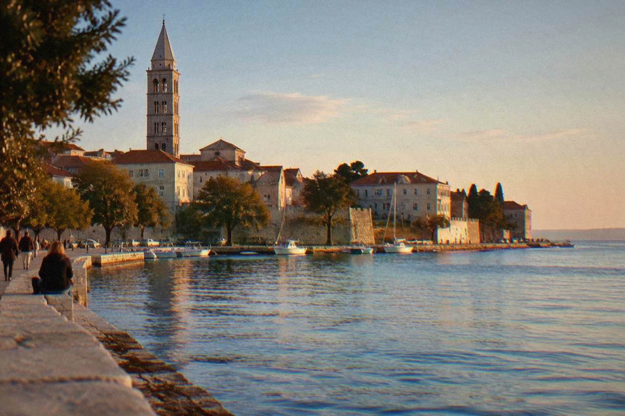 Zadar old town waterfront with terracotta roofs, bell tower and calm blue sea.