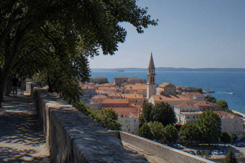 Zadar rooftops and bell tower beneath a clear blue sky from a high bastion wall.