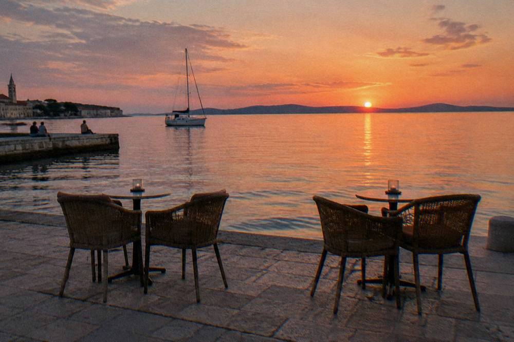 Empty cafe chairs facing the sea on a stone terrace in Zadar at a relaxed evening.