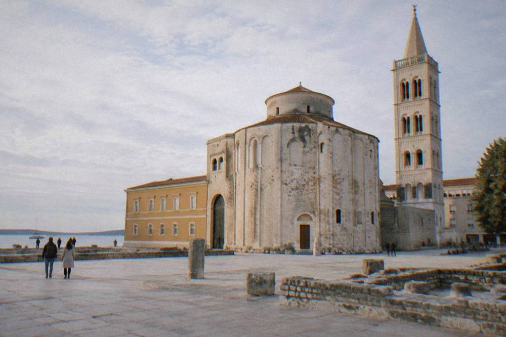 Round St Donatus church across a limestone square next to the cathedral bell tower.