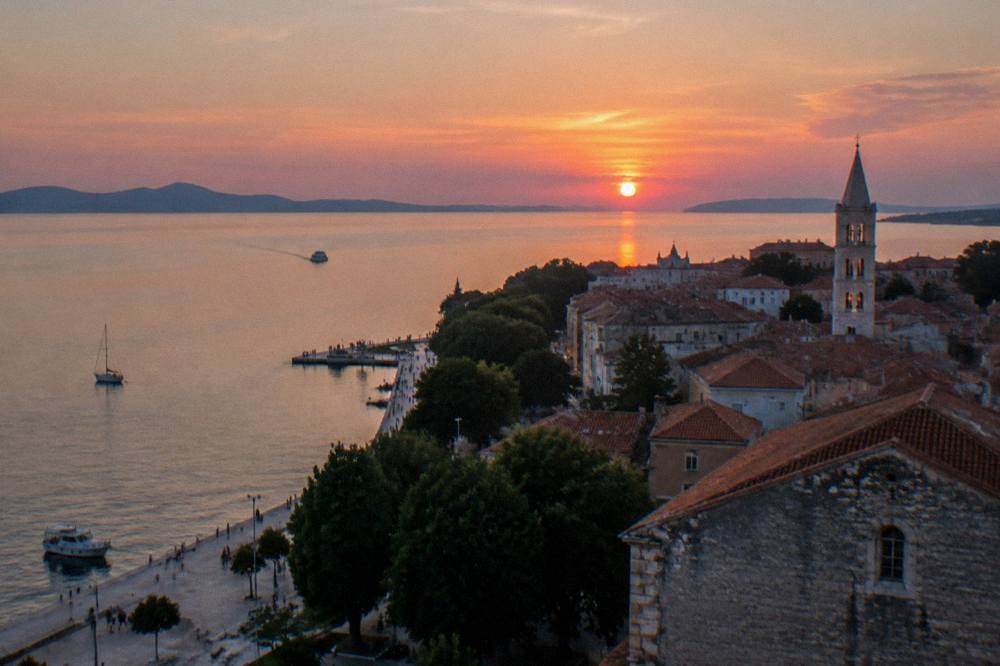 Pink sunset sky over Zadar's coast and bay above the old town roofs.