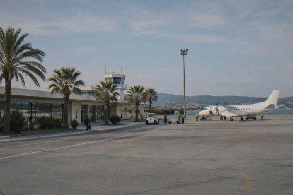The low terminal of Zadar airport with palm trees under clear sky.
