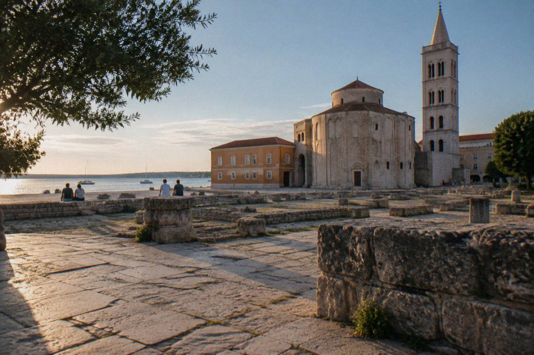 Roman forum ruins in Zadar with a few visitors in late sun