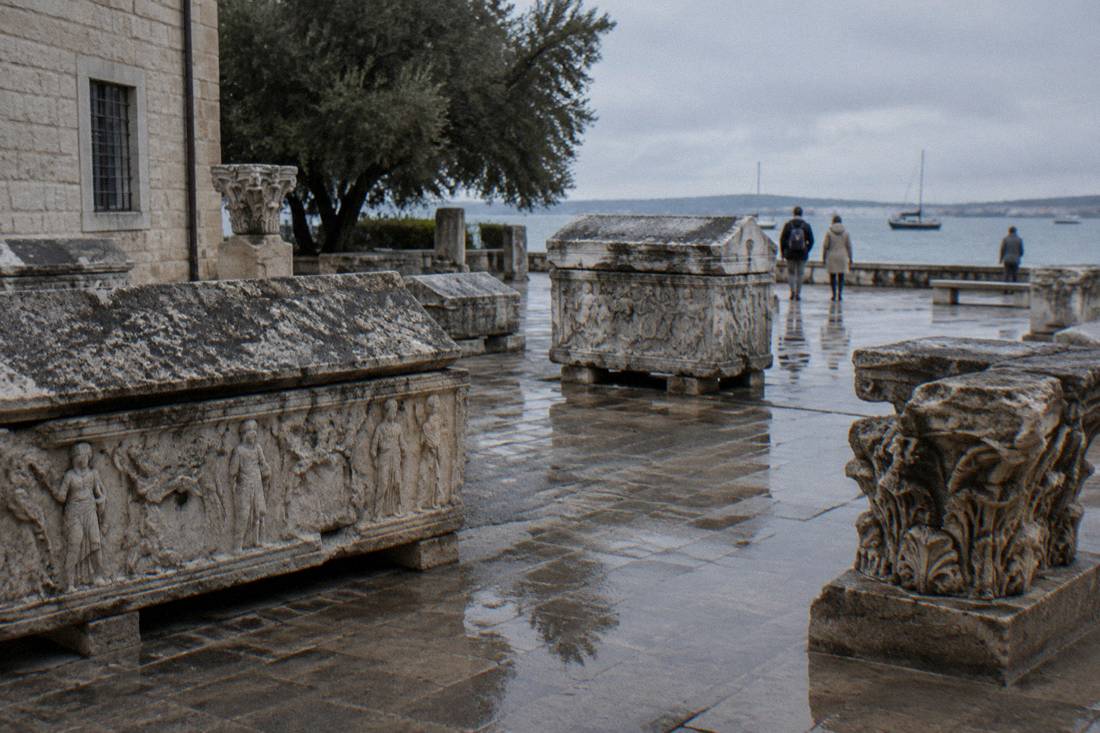 Stone sarcophagi and carved fragments in a wet museum courtyard