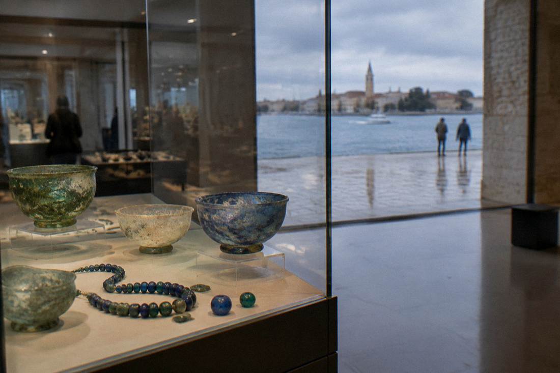 Ancient glass bowls and beads in a museum display case
