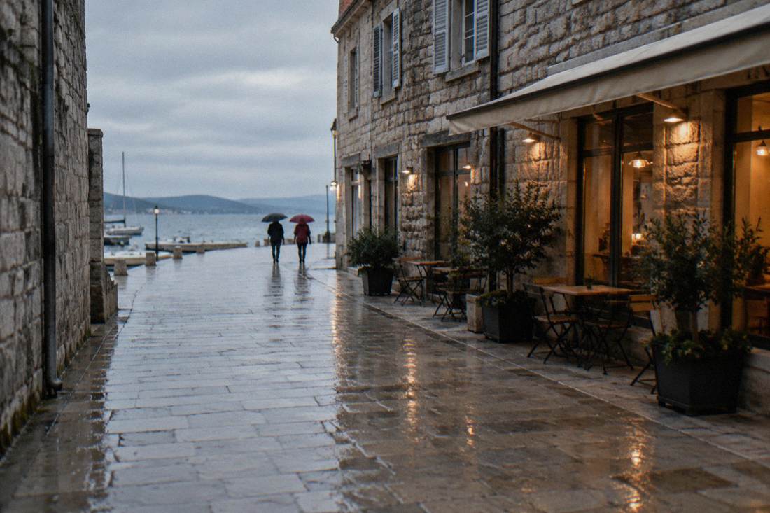 A wet limestone lane in Zadar old town with umbrellas