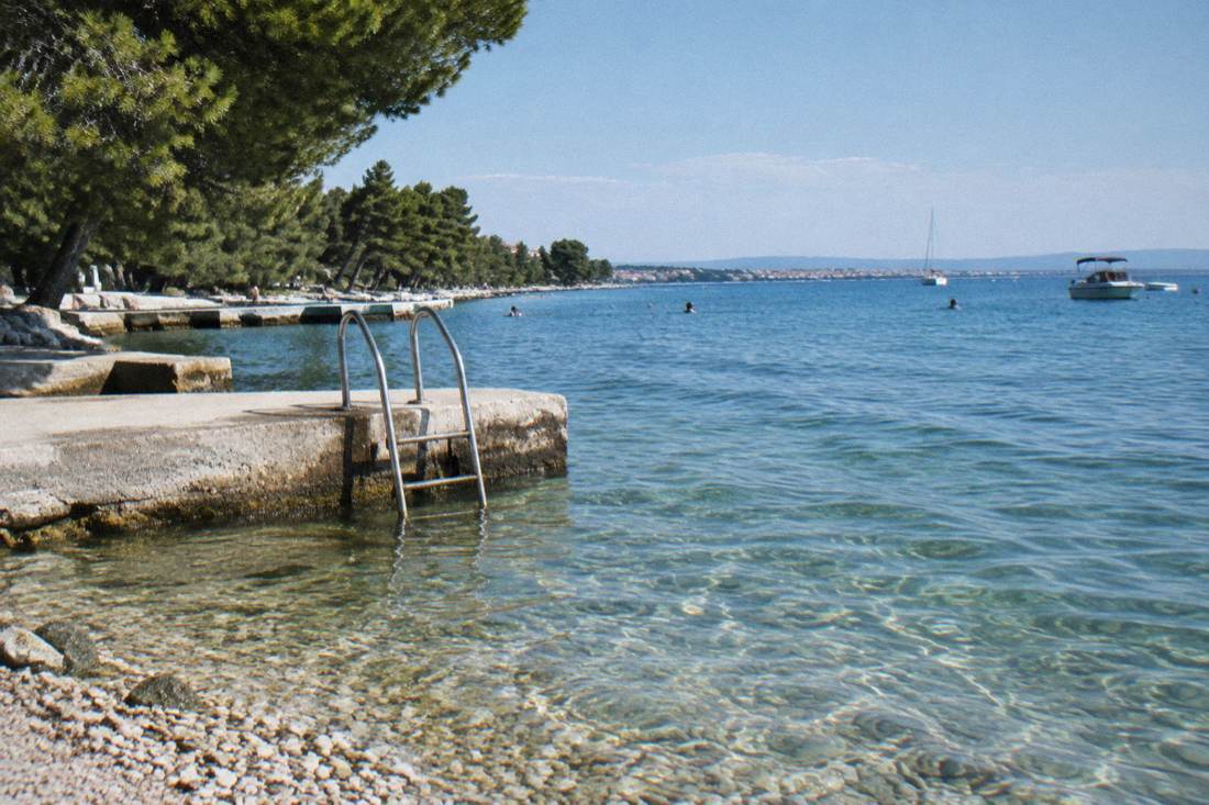 Clear shallow water and a bathing platform at a Zadar pebble beach