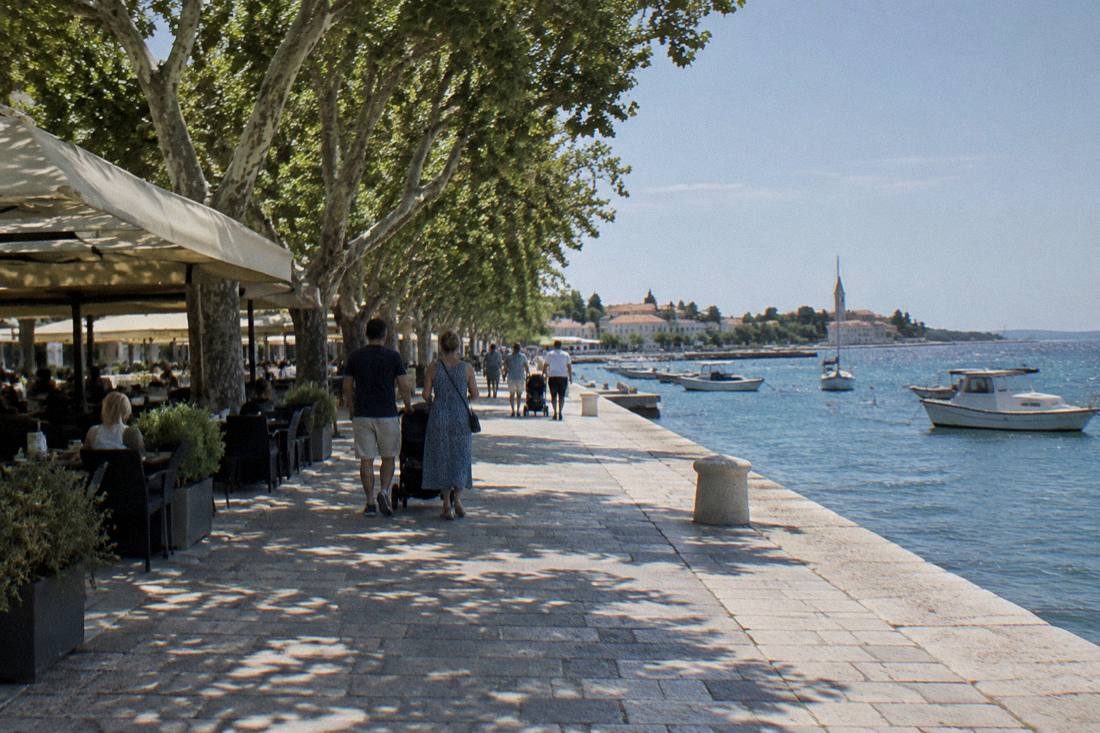 The Zadar waterfront promenade at midday with cafe tables and trees