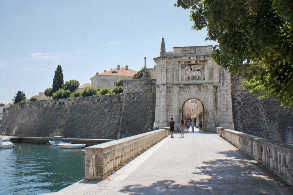 Monumental stone gate with lion above the arch in morning sun